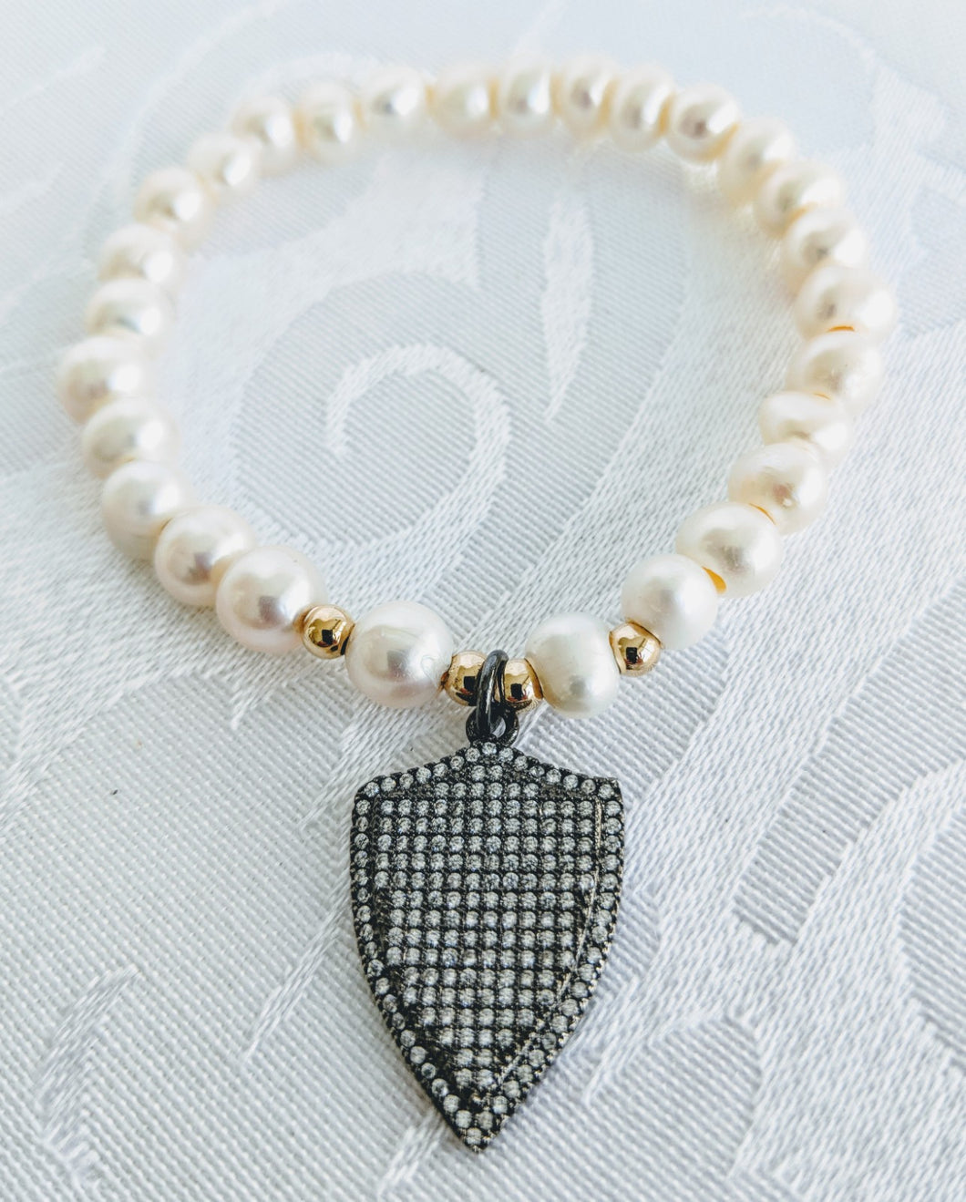 Pearl with gunmetal shield charm